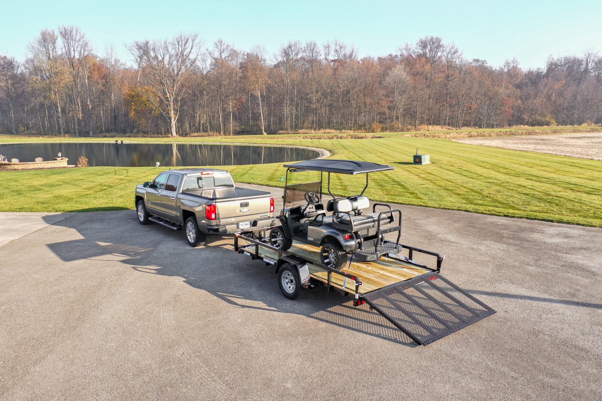 zoomed out view of a truck pulling a trailer holding a golf cart