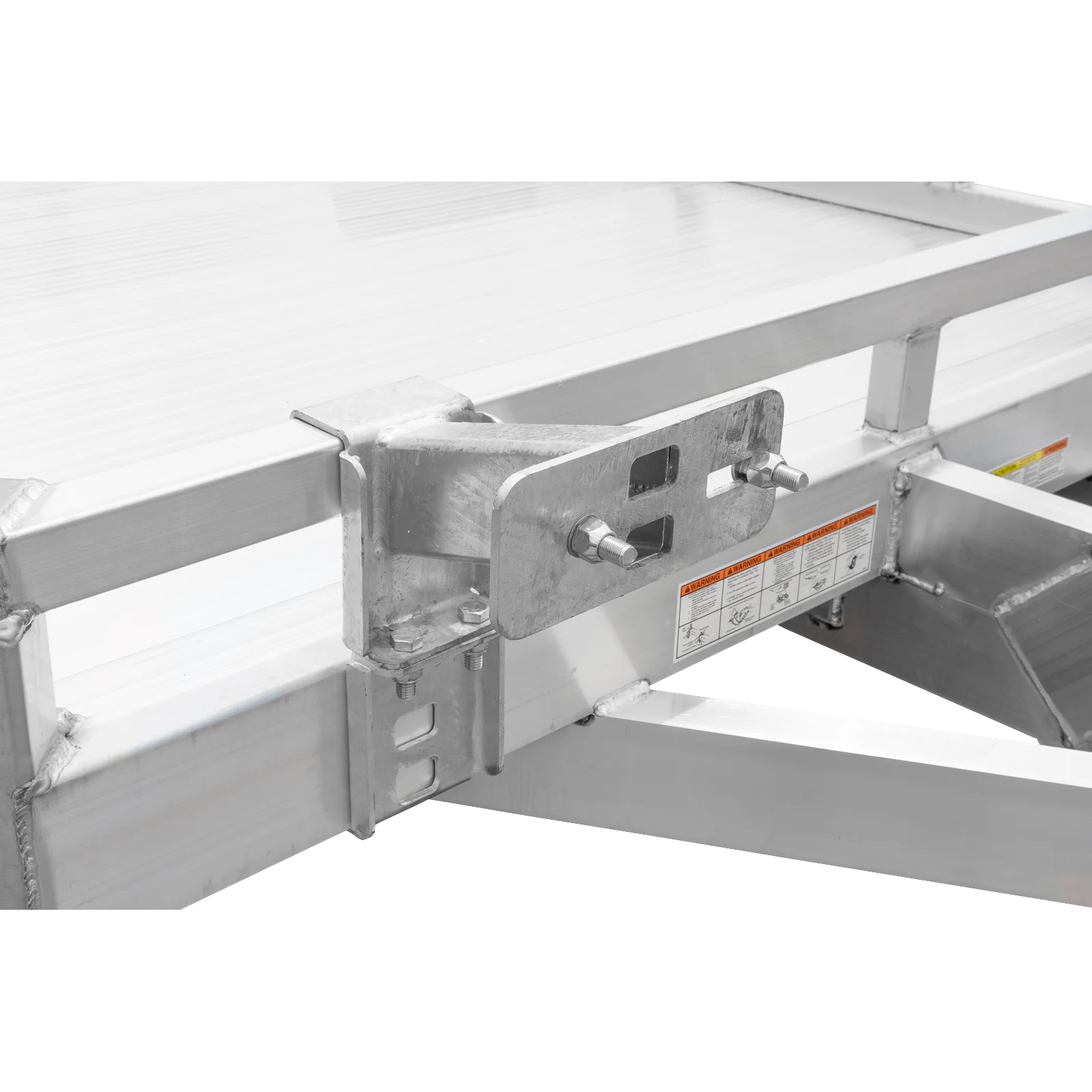 Metal mounting bracket bolted to a steel beam with an orange warning label on the frame, in an industrial setting