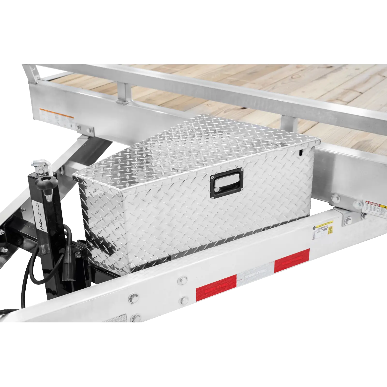 Diamond-plate metal toolbox mounted on a flatbed trailer with wooden planks and red reflective strips at the side.