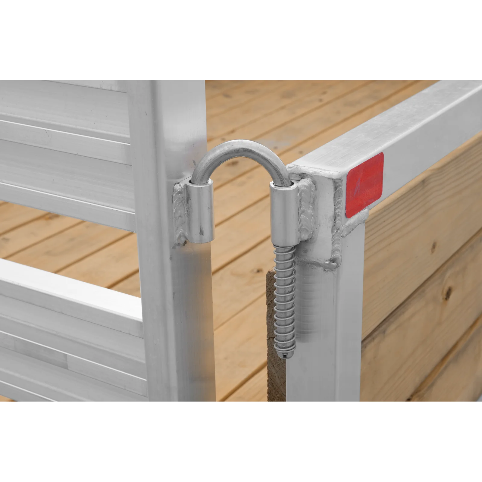Close-up of a metal padlock securing a gate latch on a silver railing with a wooden deck in the background.