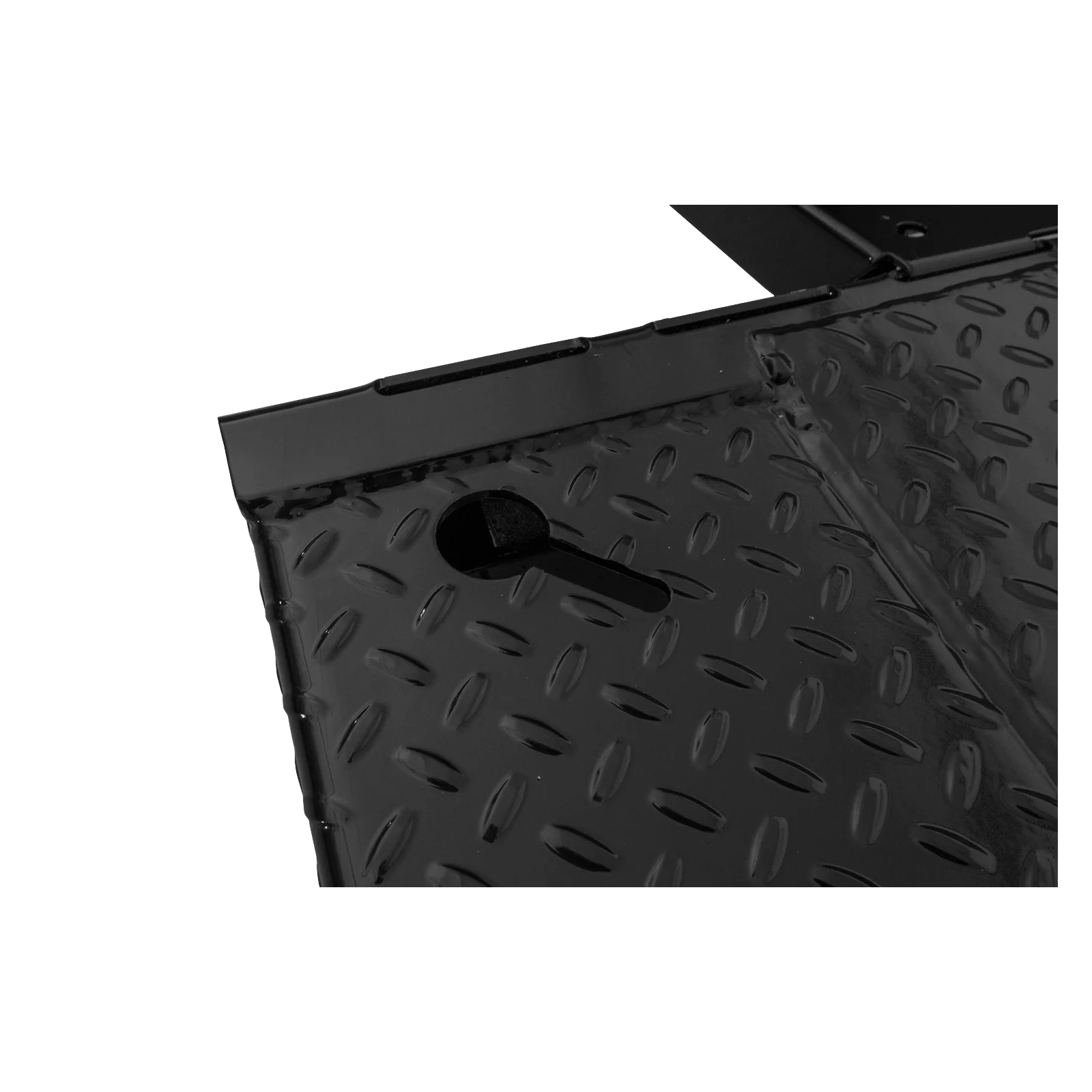 Close-up of a black diamond-plate metal surface with a circular hole and raised tread pattern edges nearby.