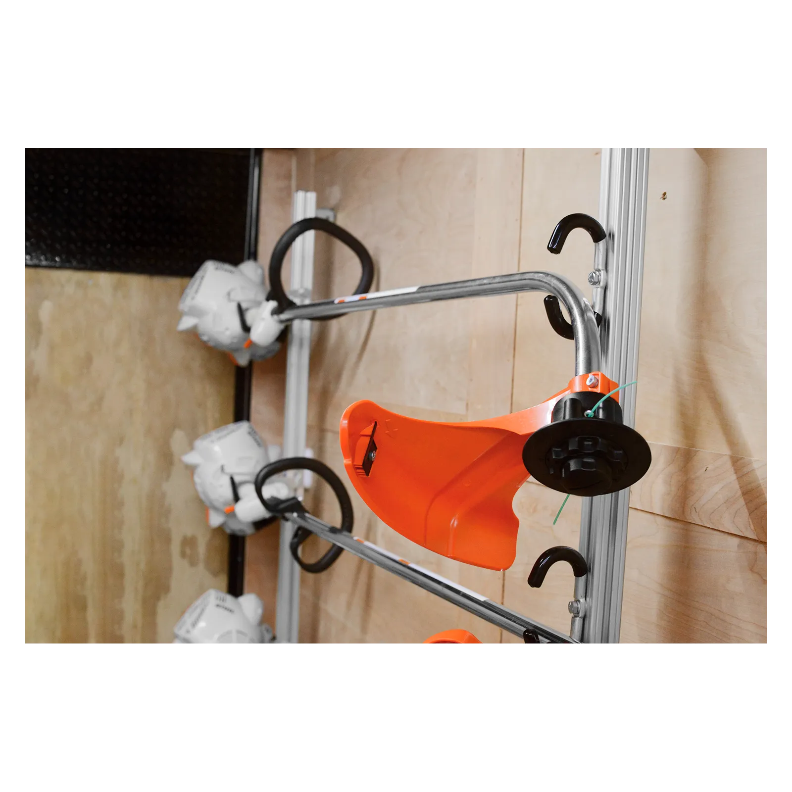 Close-up of an orange protective cover attached to a metal frame with black hooks, in a workshop setting.