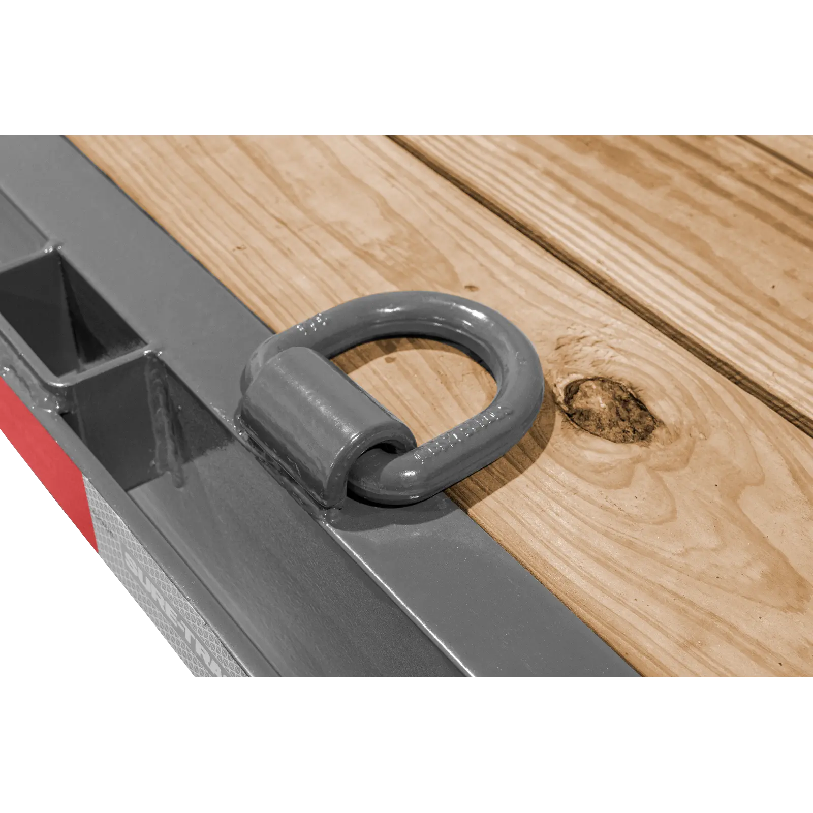 Close-up of a gray metal D-ring handle attached to a wooden surface, likely part of a toolbox or tool tray.