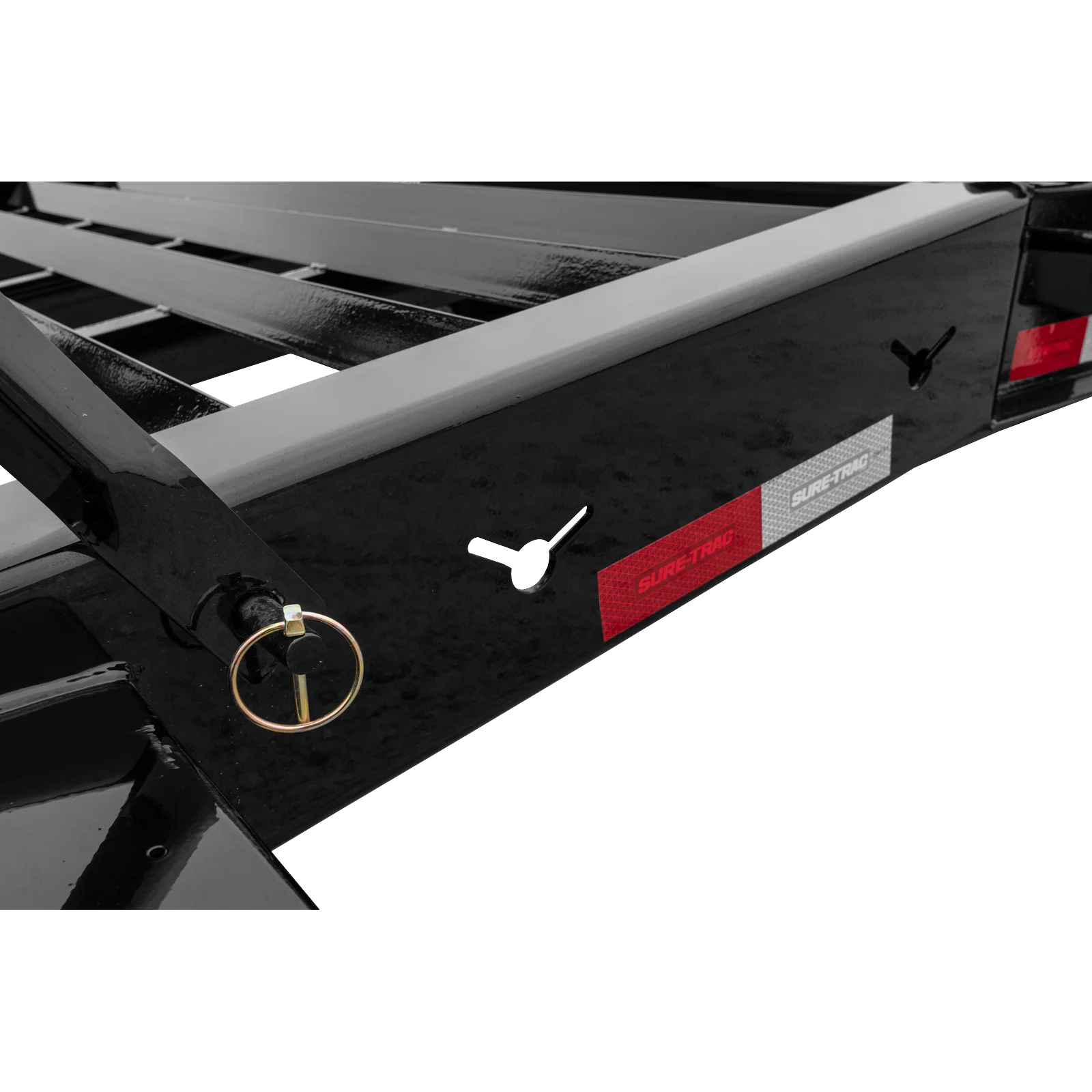 Close-up of a black trailer bed with a round hitch pin, D-ring tie-down, and red reflective strips on the side labeled Sure-Trac.