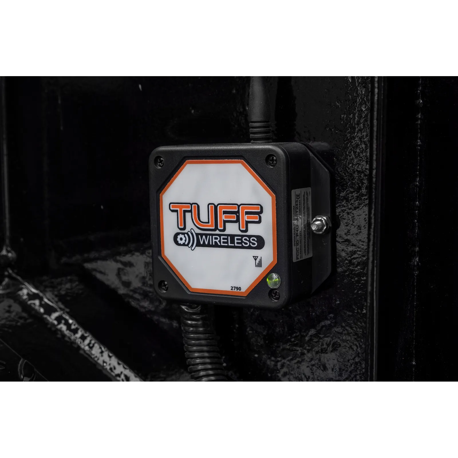 Rugged TUFF Wireless device mounted on a dark metal surface with a cable plugged into the top.