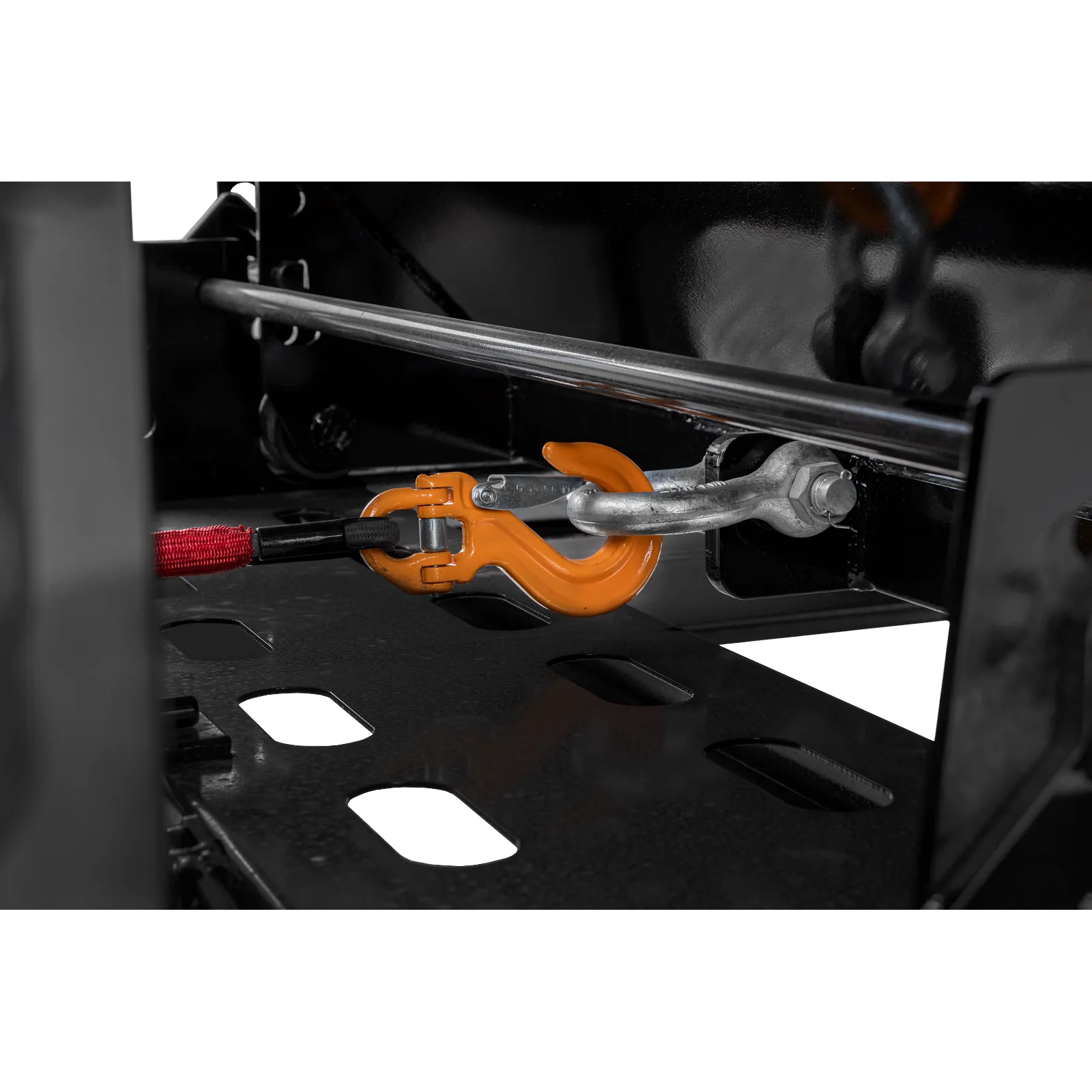 Close-up of an orange towing hook secured to a metal bracket inside a dark industrial machine frame.