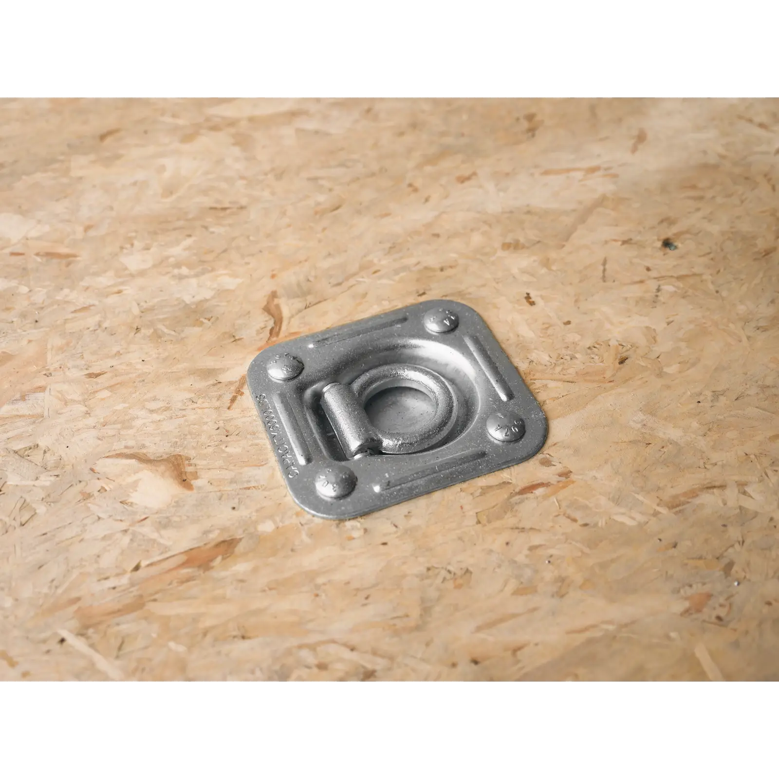 Close-up of a metal recessed tie-down anchor fixed to an OSB plywood surface with four screws